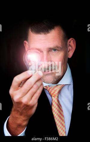 man holding an illuminated lightbulb in his hand Stock Photo