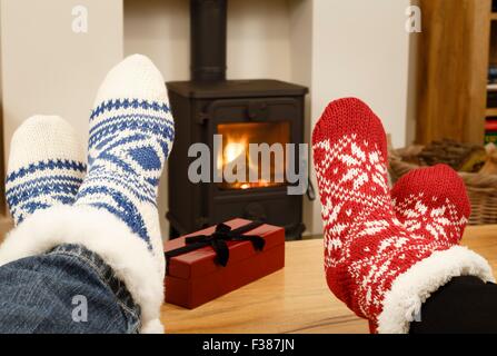 Couple relaxing in Christmas socks in front of cozy fire Stock Photo