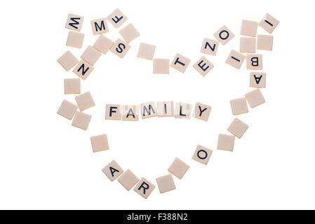 Small game tiles with letters on them arranged in a heart surrounding the word 'love' isolated on a white background. Stock Photo