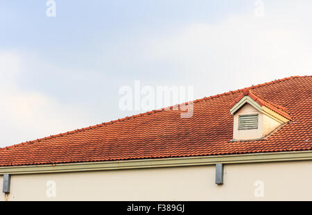 Chimneys on roof of red tiles with blue sky and clouds. Stock Photo