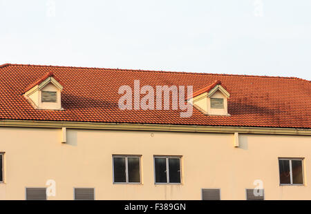 Chimneys on roof of red tiles with blue sky and clouds. Stock Photo