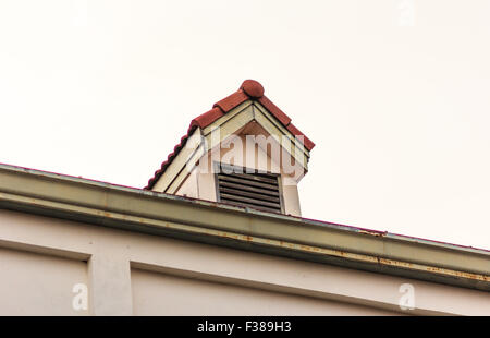 Chimneys on roof of red tiles with blue sky and clouds. Stock Photo