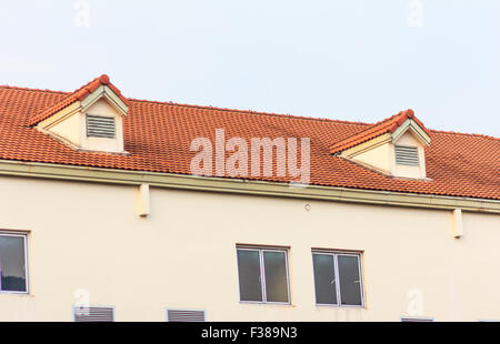 Chimneys on roof of red tiles with blue sky and clouds. Stock Photo