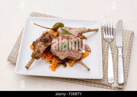 Grilled racks of lamb with carrot, onion, garlic and capers Stock Photo