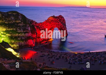 Durdle Door, Dorset, UK. 1st October, 2015. Crowds gathered at the  famous landmark of Durdle Door on Dorset’s Jurassic Coast as it is lit up by a team of lighting designers to celebrate the International Year of Light where a Bournemouth based design team created a scene which they described as reminiscent of an impressionist painting. The event is part of a 'Night of Heritage Light' where lighting installations will illuminate 10 UNESCO World Heritage Sites across the UK and Ireland. Credit:  Tom Corban/Alamy Live News Stock Photo