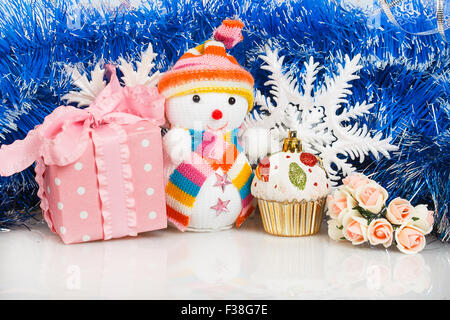 Snowman with pink gift box and white snowflakes on a background of blue garland Stock Photo