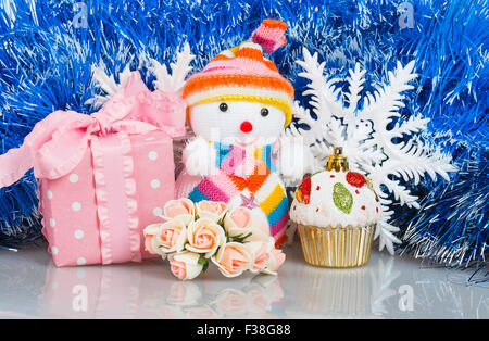 Snowman with pink gift box and white snowflakes on a background of blue garland Stock Photo