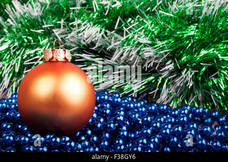 orange Christmas ball and blue beads on a background of green garland Stock Photo