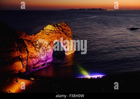 Durdle Door, Dorset, UK. 1st October, 2015. Crowds gathered at the  famous landmark of Durdle Door on Dorset’s Jurassic Coast as it is lit up by a team of lighting designers to celebrate the International Year of Light where a Bournemouth based design team created a scene which they described as reminiscent of an impressionist painting. The event is part of a 'Night of Heritage Light' where lighting installations will illuminate 10 UNESCO World Heritage Sites across the UK and Ireland. Credit:  Tom Corban/Alamy Live News Stock Photo