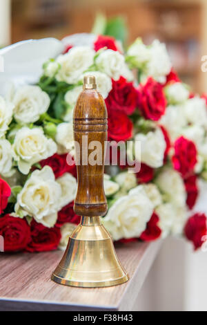 Old school bell with yellow flowers. Last call, graduation. Stock Photo