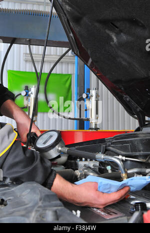 Car servicing mechanic pouring fresh oil to engine Stock Photo