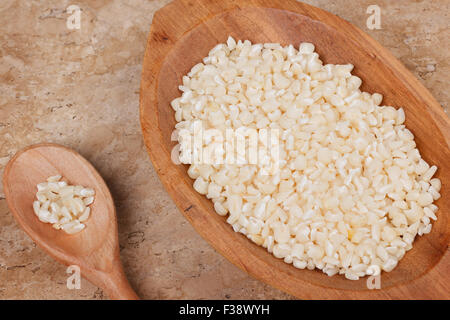 White grated corn kernels in wooden bowl with spoon on marble table. Selective focus Stock Photo