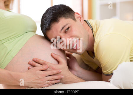 Husband listening to stomach of  his pregnant wife Stock Photo