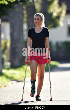 Young woman with crutches, walking with a foot injury, with a plaster splint, Germany Stock Photo