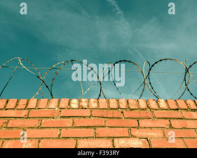 Barbed Or Razor Wire On Top Of A Red Brick Wall Around Private Property Stock Photo