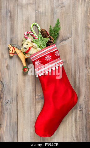 Christmas stocking with nostalgic vintage toys decoration and pine branch over wooden background Stock Photo