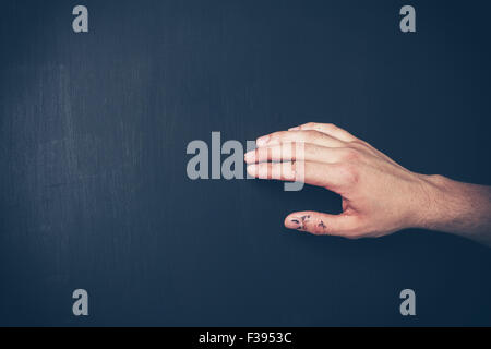 A hand is touching a freshly painted black wall Stock Photo