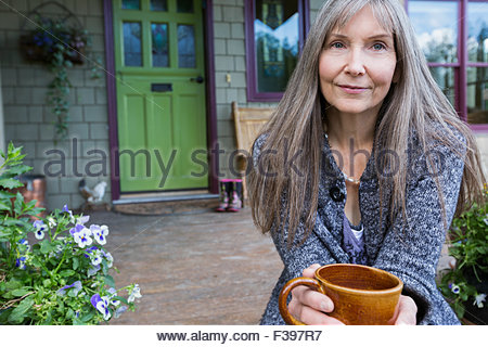Portrait woman drinking coffee in front stoop