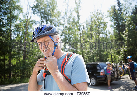 Senior man fastening mountain biking helmet