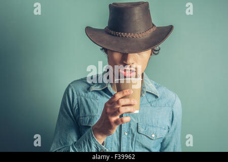 Young cowboy is drinking coffee from a paper cup Stock Photo