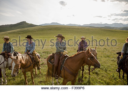 Female ranchers on horseback in sunny remote field