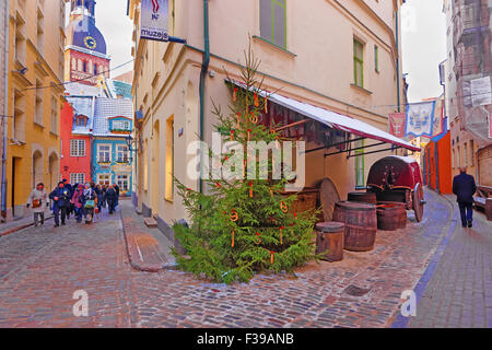 RIGA, LATVIA - DECEMBER 28, 2014: Group of tourists exploring old charming Riga with its narrow medieval streets at Christmas Stock Photo