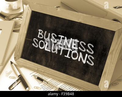 Business Solutions Handwritten by white Chalk on a Blackboard. Composition with Small Chalkboard on Background of Working Table Stock Photo