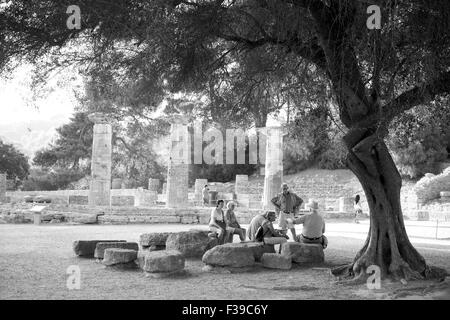 Tourist having a rest underneath  an olive tree  , temple of Hera at ancient Olympia on the background. Stock Photo