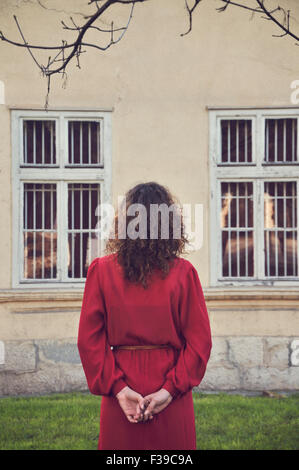 Woman in red dress standing outdoors, rear view Stock Photo