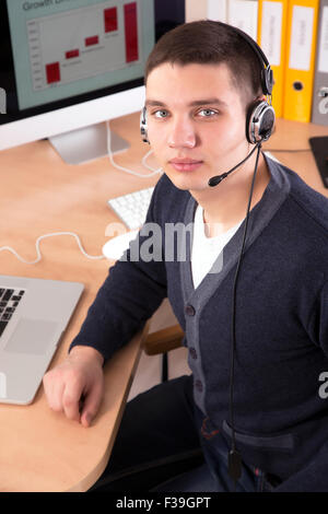 Young businessman with headset on in the office interior Stock Photo