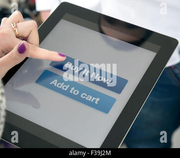 Female fingers clicking on BUY button on the screen of tablet PC Stock Photo