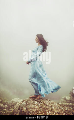 Portrait of a mid adult woman standing on rocks in the mist Stock Photo