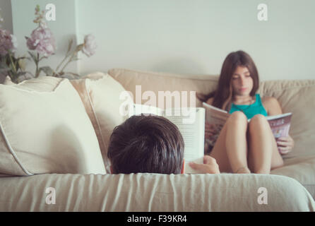 Teenage boy and girl sitting in the sofa reading books Stock Photo