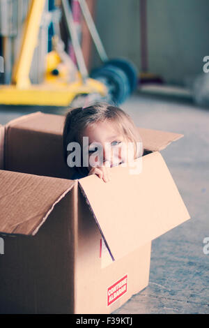 Smiling Girl sitting inside a cardboard box Stock Photo