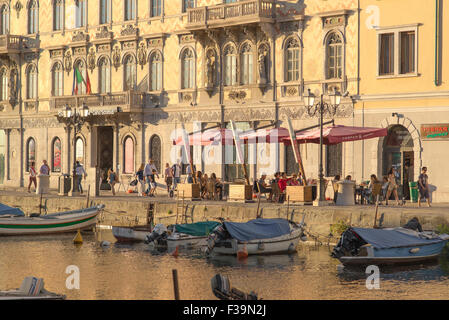 Trieste summer, view on a summer afternoon of people relaxing at cafe tables sited on a terrace beside the Canal Grande in Trieste, Italy. Stock Photo