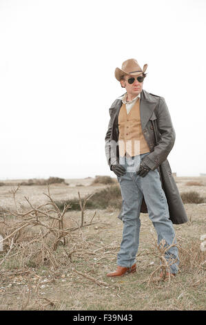 Modern day cowboy, standing in the the middle of a barren landscape. Stock Photo