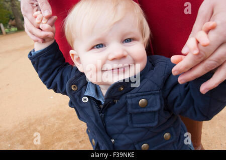 Baby walking whilst holding his mums hands for balance. Stock Photo