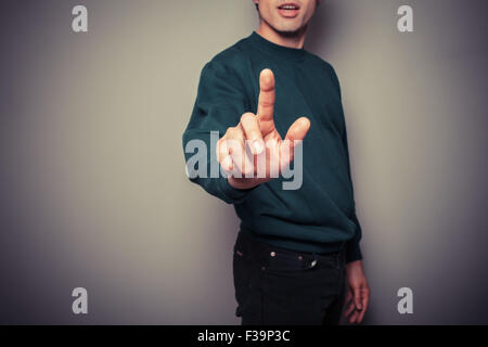 A young man is pointing or pushing a button with his finger Stock Photo