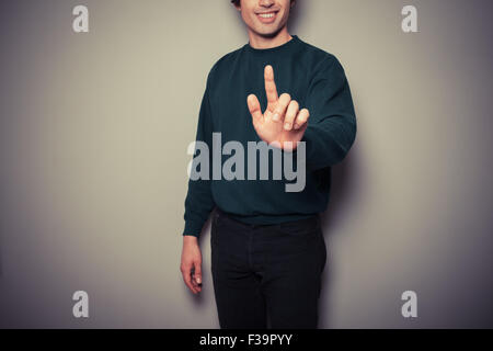 A young man is pointing or pushing a button with his finger Stock Photo