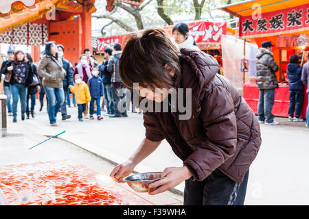 Caucasian child,  boy, 9-10 year old, gold fish fishing from stall at Shinto Shrine entrance. 'Kingyo sukui' is a popular child's game in Japan. Stock Photo