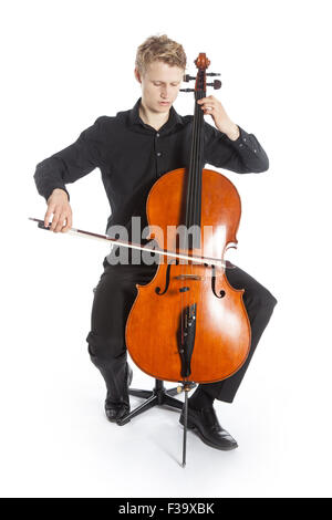 young blond caucasian man sits and plays the cello in studio against white background Stock Photo