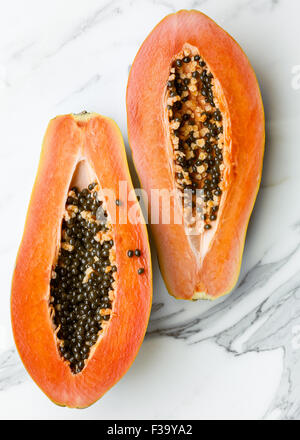 A Papaya cut in half on marble surface Stock Photo