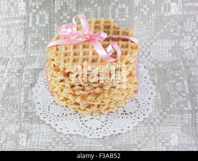 round wafers tied with a pink ribbon on a gray background Stock Photo