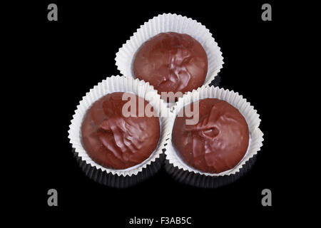 Three chocolate candies isolated on a black background Stock Photo