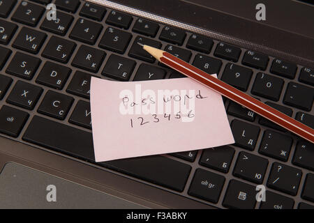 Sticky note with password and pencil on black laptop Stock Photo