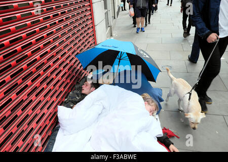 Two young homeless people person couple sleeping rough on the pavement under an umbrella at Bishopsgate in London England UK  KATHY DEWITT
