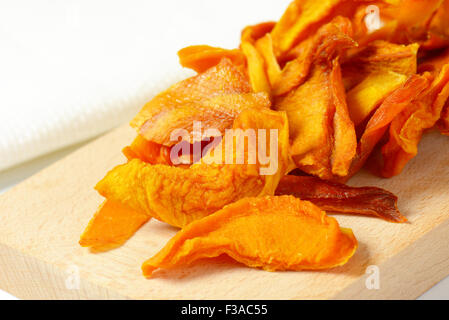 heap of dried mango slices on wooden cutting board Stock Photo