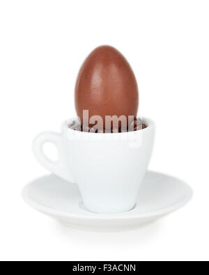 chocolate egg on a white cup and saucer isolated on white background Stock Photo