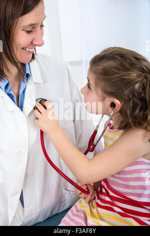 MODEL RELEASED. Female doctor using a stethoscope to examine a young ...