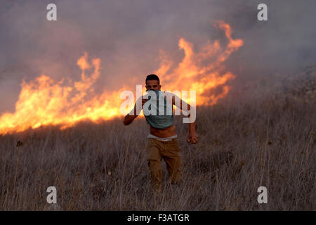 Nablus, West Bank, Palestinian Territory. 3rd Oct, 2015. Palestinian protesters stand amid blazes of fire during clashes with Israeli settlers in the West Bank village of Burin on October 3, 2015. Sporadic clashes erupted between Palestinians and a dozen settlers from the settlement of Yitzhar, which is known as a bastion of extremists, when the settlers threw stones at Palestinians who responded in the same way © Nedal Eshtayah/APA Images/ZUMA Wire/Alamy Live News Stock Photo